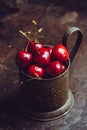 Ripe and juicy cherries in old metal cup on the dark rustic background Royalty Free Stock Photo