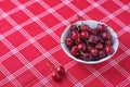 Ripe juicy cherries with water drops in a ceramic bowl on a table with a red tablecloth. Summer berries Royalty Free Stock Photo