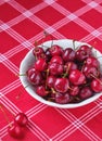 Ripe juicy cherries with water drops in a ceramic bowl on a table with a red tablecloth. Summer berries Royalty Free Stock Photo