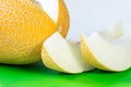 Ripe juicy melon with two slices on bright green and white background Royalty Free Stock Photo