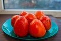 Ripe, juicy orange persimmon on a bluish green plate
