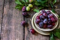 Ripe juicy plums in a bowl on a wooden background. Royalty Free Stock Photo