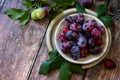 Ripe juicy plums in a bowl on a wooden background. Royalty Free Stock Photo