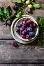 Ripe juicy plums in a bowl on a wooden background. Top view flat lay. Royalty Free Stock Photo