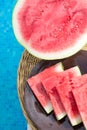 Ripe Juicy Seedless Halved Watermelon Slices Wedges on Plate on Rattan Table by Swimming Pool. Sunlight. Vacation Relaxation