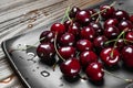 Ripe juicy sweet cherries in a black plate on a wooden background. Top view wet fresh cherries with water drops Royalty Free Stock Photo