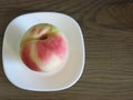 Ripe large peach on a white plate