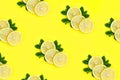 Ripe lemons pattern. Three slices of lemon lie on mint leaves on bright yellow background Royalty Free Stock Photo