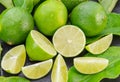 Ripe lime fruits with slices and lime leaves on a gray stone table