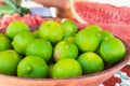 Ripe limes in bowl and watermelon slices. Sweet tropical fruits. Juicy fruits. Fresh limes. Citrus harvest. Colorful fruits. Royalty Free Stock Photo