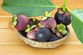 Ripe mangosteens Garcinia mangostana with green leaves in a basket on the wooden table