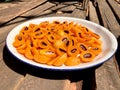 Ripe marian plum or plum mango fruits in white tray on wooden floor and dried in sun light. Lateral view