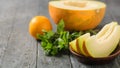 Ripe melon pieces on a clay bowl, banana, mint and orange on a rustic wooden table. Royalty Free Stock Photo