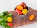 Ripe multicolored cherry tomatoes in a small zinc or metal bucket and parsley on a brown wooden cutting board. Vegetables,