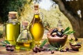 Ripe natural olives with bottles of olive oil on a vintage old wooden table on a background of olives garden