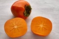 Ripe orange persimmon whole fruit and sliced sliced on a white wooden table