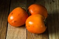 Ripe orange persimmons on an aged wood table
