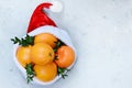 Ripe oranges in the hat of Santa Claus with boxwood plant on a blue background. Festive mood, Christmas and New Year.