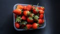 Ripe organic strawberries in a plastic container on a black table background. View from the top, . Royalty Free Stock Photo