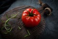 Ripe organic tomato and rosemary sprig on an old chopping board. A crack in a tomato. Selective focus