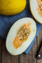 Ripe organic yellow melons, halved and whole on dark plank wood background, pulp and seeds, blue linen napkin, knife Royalty Free Stock Photo