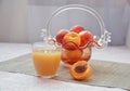 Ripe peaches and glass of juice on a table, cut peach, of a beautiful vase in the shape of a basket background. Royalty Free Stock Photo