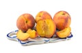Ripe peaches, whole and cut into slices on a ceramic tray close-up, white isolated background, horizontal view