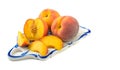 Ripe peaches, whole and cut into slices on a ceramic tray close-up, white isolated background, horizontal view