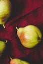 Ripe pears on a red linen tablecloth, food background