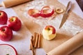 Ripe peeled apple, knife, cinnamon, flour, parchment paper on the table. Preparation for cooking pastry Royalty Free Stock Photo