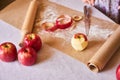 Ripe peeled apple, knife, cinnamon, flour, parchment paper on the table. Preparation for cooking pastry Royalty Free Stock Photo