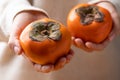 Ripe persimmon fruit holding by hand Royalty Free Stock Photo