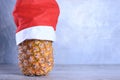 Ripe pineapple, ananas with glasess in Santa`s hat. New Year fruit concept