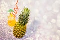 Ripe pineapple and a glass of fruit nectar with ice on a gray glittering background