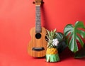 Ripe pineapple in green skirt, guitar monstera leaves coral background. The concept of relaxation and a Hawaiian party.