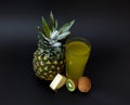 Ripe pineapple, ripe kiwi slices and a glass of fresh fruit juice on a black background Royalty Free Stock Photo