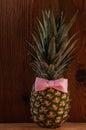 Ripe pineapple with ribbon bow on wooden background. Healthy food, tropical fruits, slimming vegan foods, weight loss