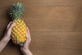 Ripe pineapple with various gestures of women hand holding on wooden background