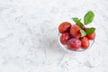 Ripe plum cherry plum in a glass bowl and green leaves on a light concrete background. Copy space for text. Royalty Free Stock Photo