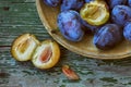 Ripe plum in wooden plate, on old table Royalty Free Stock Photo