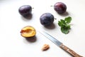 Ripe plums on the kitchen table, knife and plum slice with a stone, top view, close-up