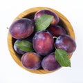 Ripe plums and leaves in a bowl isolated on white background. Top view. File contains clipping path Royalty Free Stock Photo