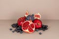 Ripe pomegranate cut in half with juicy seeds, apples, black grapes, fig slices, blueberry, red currant on beige Royalty Free Stock Photo