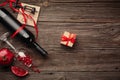 Ripe pomegranate fruit with a glass of wine, a bottle and a gift on a wooden background