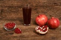 Ripe pomegranate fruits with glass of juice on wooden table Royalty Free Stock Photo