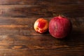 Ripe pomegranate with peach lying on the dark wooden table