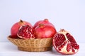 Ripe pomegranates on basket on grey background