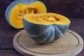 A ripe pumpkin, with bright orange flesh, cut in half on an old wooden table Royalty Free Stock Photo