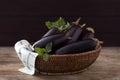 Ripe purple eggplants and basil in wicker bowl on wooden table, closeup Royalty Free Stock Photo