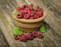 Ripe raspberries with green leaves in a bowl on a wooden table Royalty Free Stock Photo